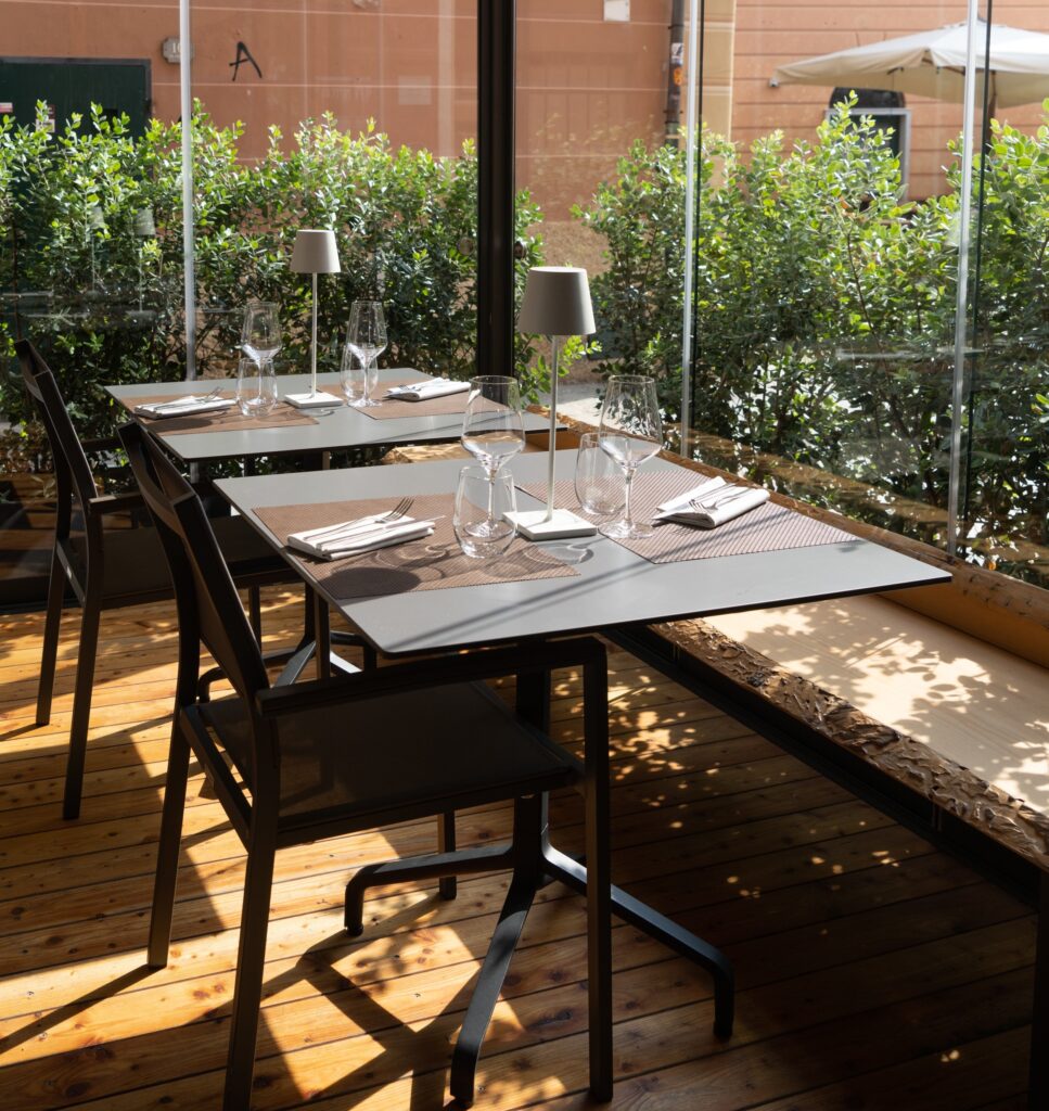 tavoli e sedute esterni ferro bar piante arredo panche di legno vetrate trasparenti ristorante