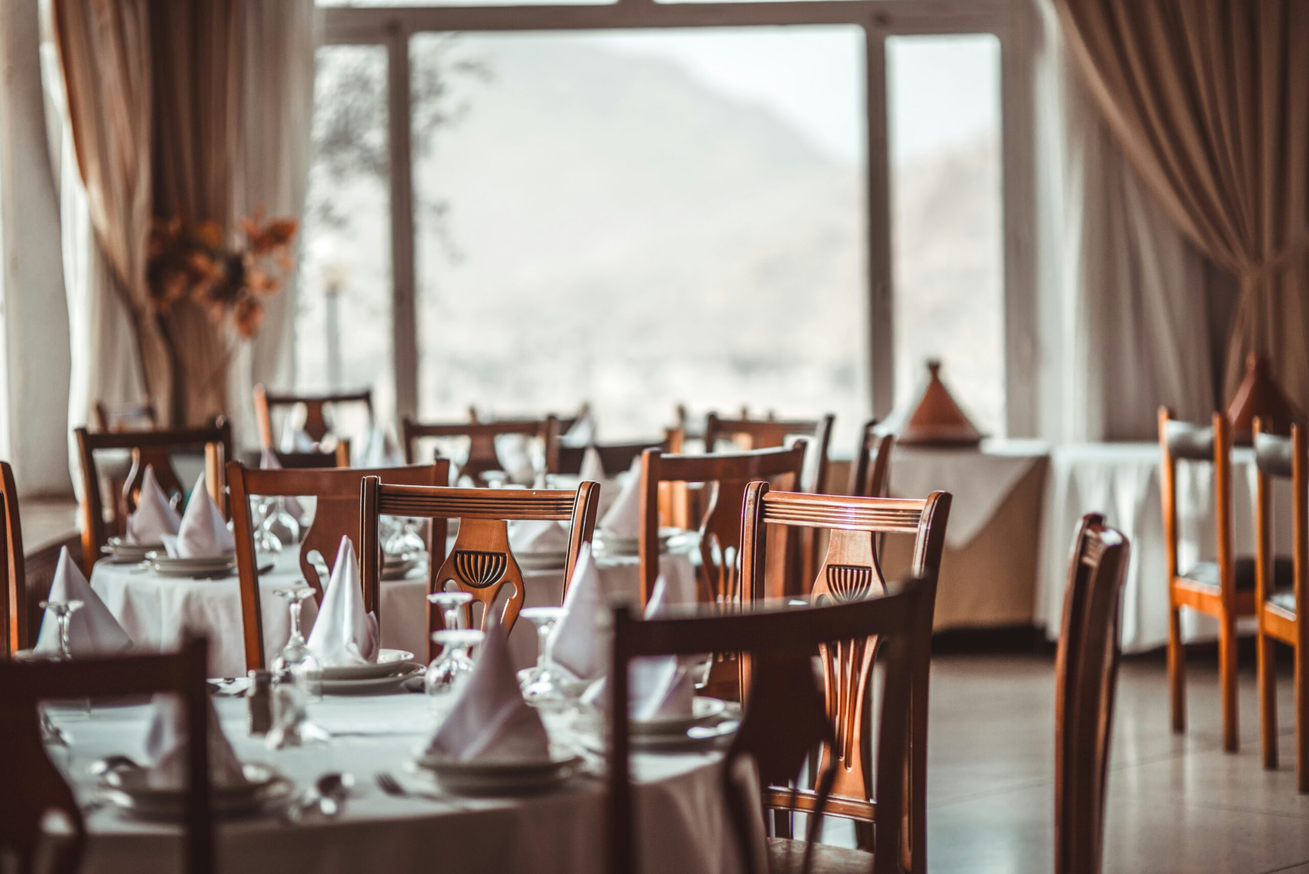 ristorante sedie di legno apparecchiato fazzoletti bianchi piegati tovaglia bianca elegante arredato arredo